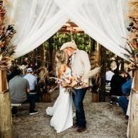 Couple embracing under white drapes at an outdoor wedding reception