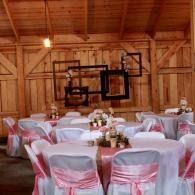 Decorated banquet tables with pink chair sashes in a wooden barn hall