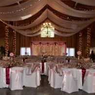 Elegant banquet hall with draped ceiling, twinkling lights, and decorated tables set for an event