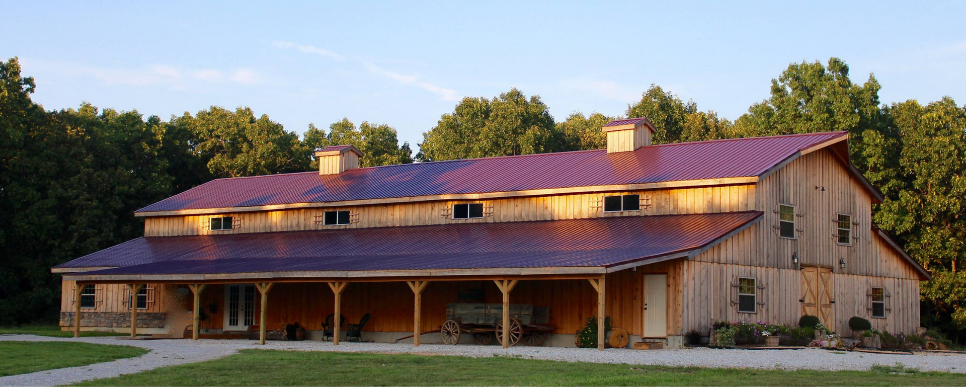 Rustic barn-style house with a long porch and metal roof at sunset