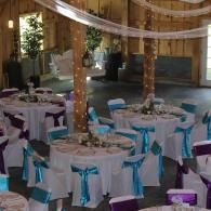 Decorated banquet hall with round tables, white linens, and turquoise chair sashes