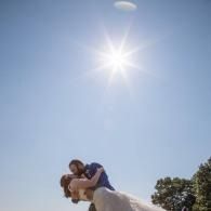 Couple embracing outdoors beneath a bright sun in a blue sky