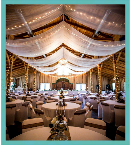 Elegant banquet hall with round tables, white draped ceiling, and warm golden lighting