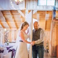 Bride and man adjusting hands together in a warmly lit wedding venue
