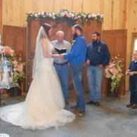 Wedding ceremony with bride in white gown and groom at altar inside a wood-paneled church