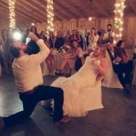 Couple dancing at a warmly lit wedding reception while guests watch and take photos