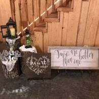 Decorative fall porch display with lanterns, greenery, and rustic signs against a wooden staircase and fence