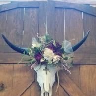 Floral arrangement on a longhorn skull mounted on a wooden barn door