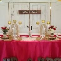 Decorated altar table with pink cloth, candles, flowers, and a white backdrop with a sign above