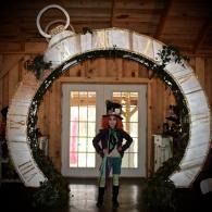 Person standing under a large white circular arch in a rustic indoor setting