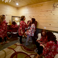Several people in red floral robes relax and chat in a wood-paneled lounge with patterned carpet.