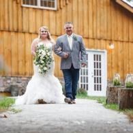 Bride and man walking down a path in front of a wooden building