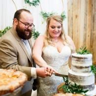 Couple cutting a tiered wedding cake at a rustic reception