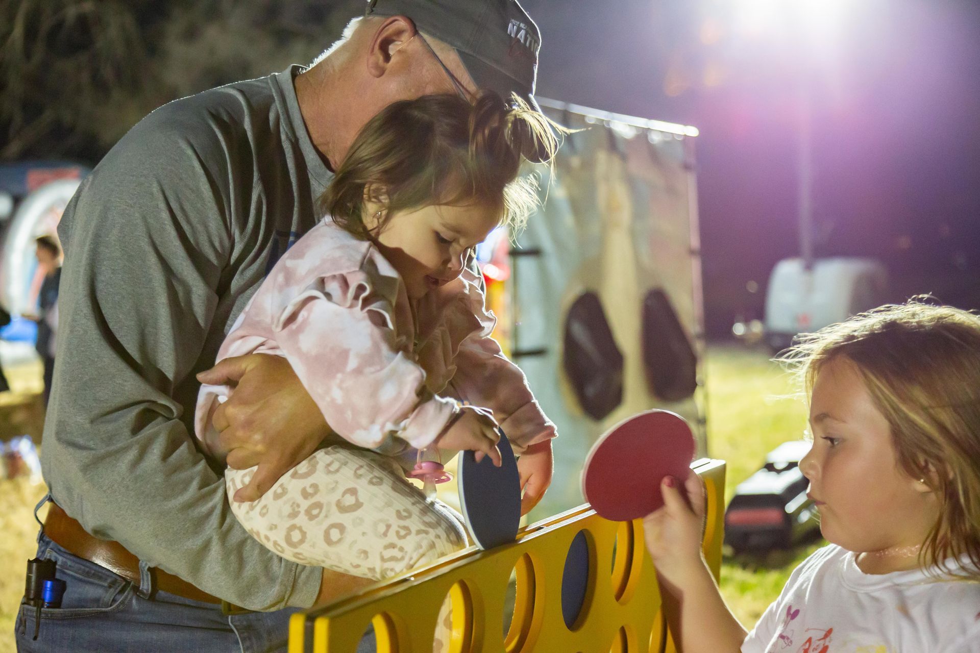 Professional photograph of a man holding a baby with a ping pong paddle.