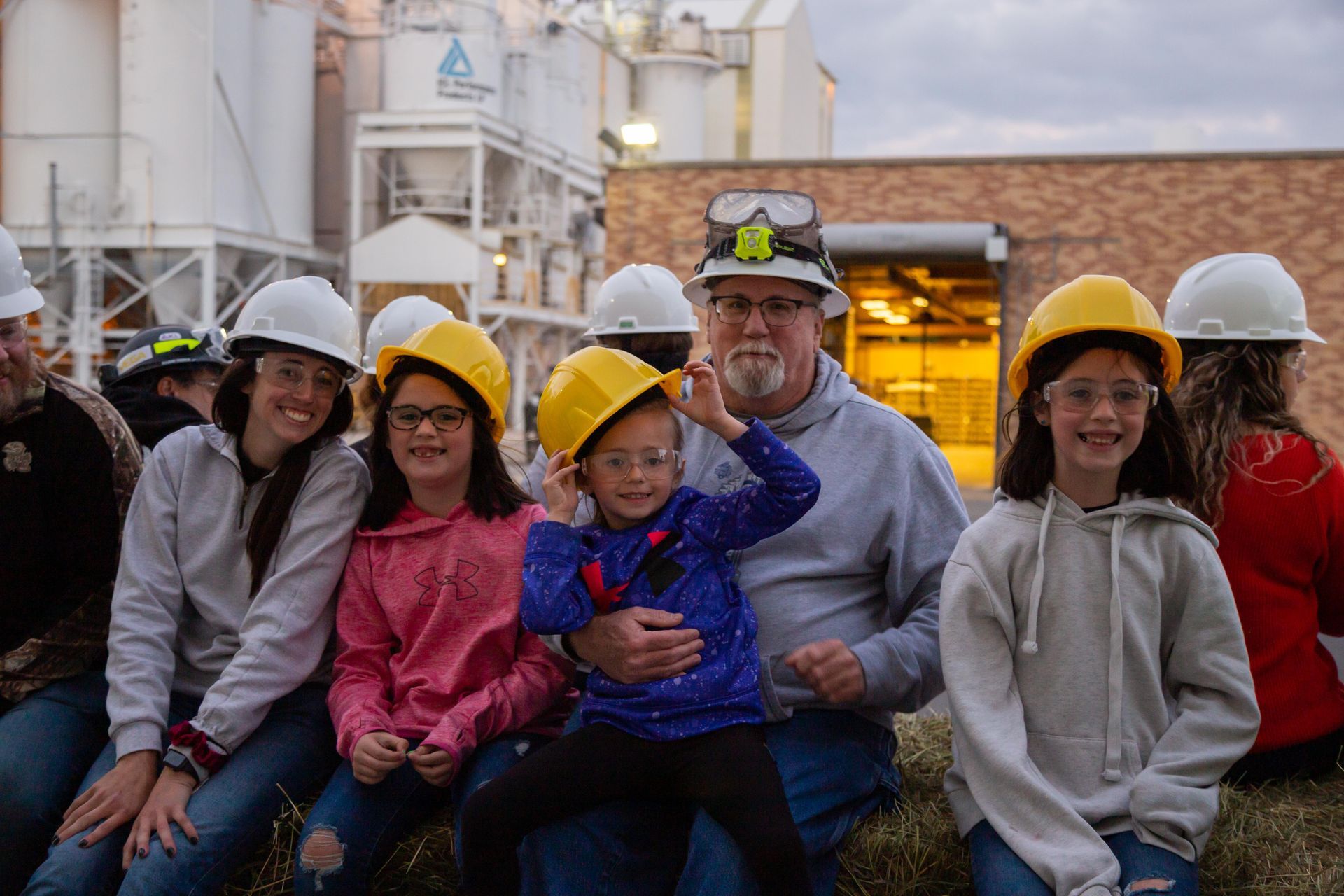 Professional photograph of family wearing hard hats at a factory.