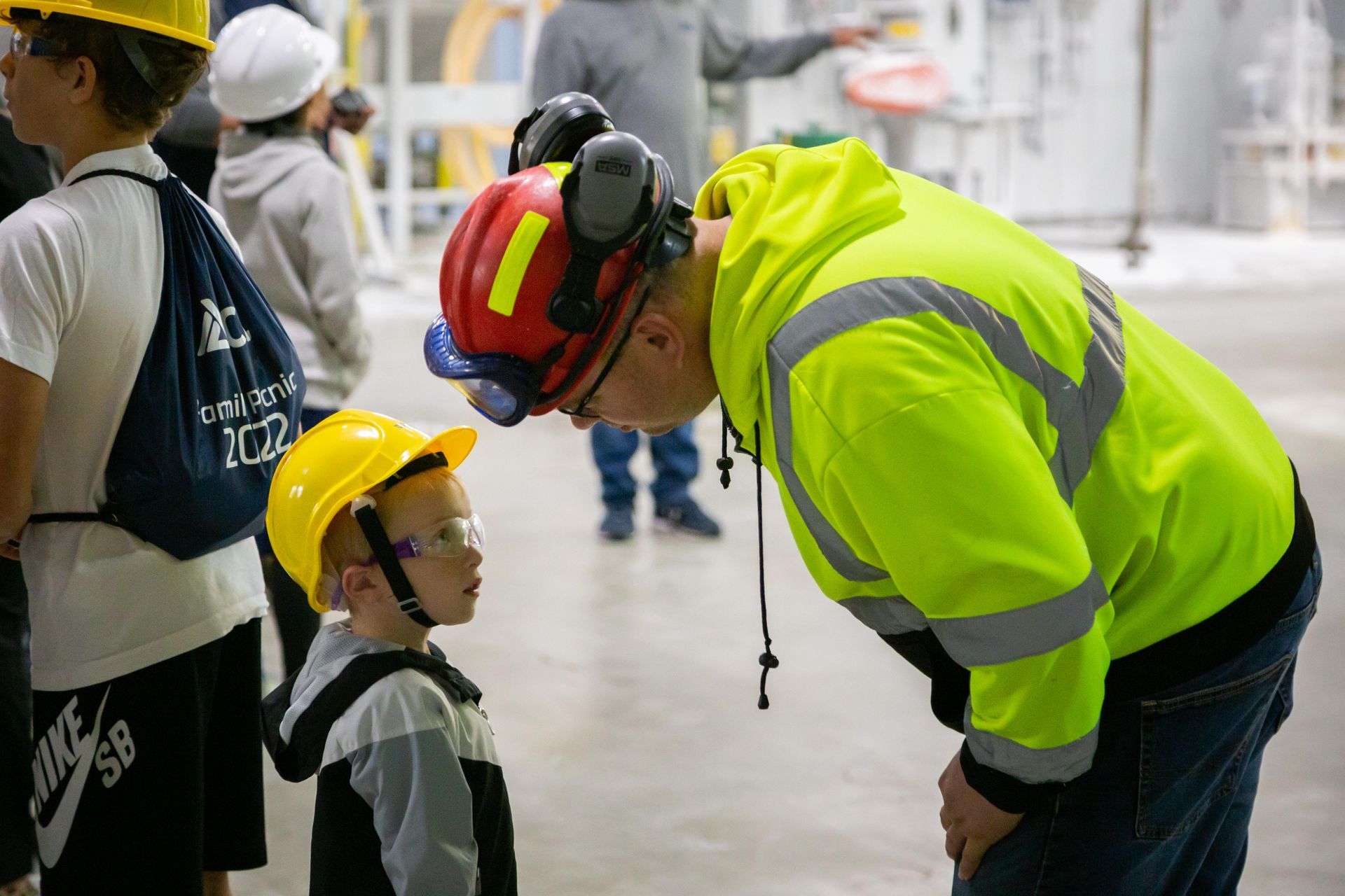 Professional photograph of a factory work talking to a little boy..