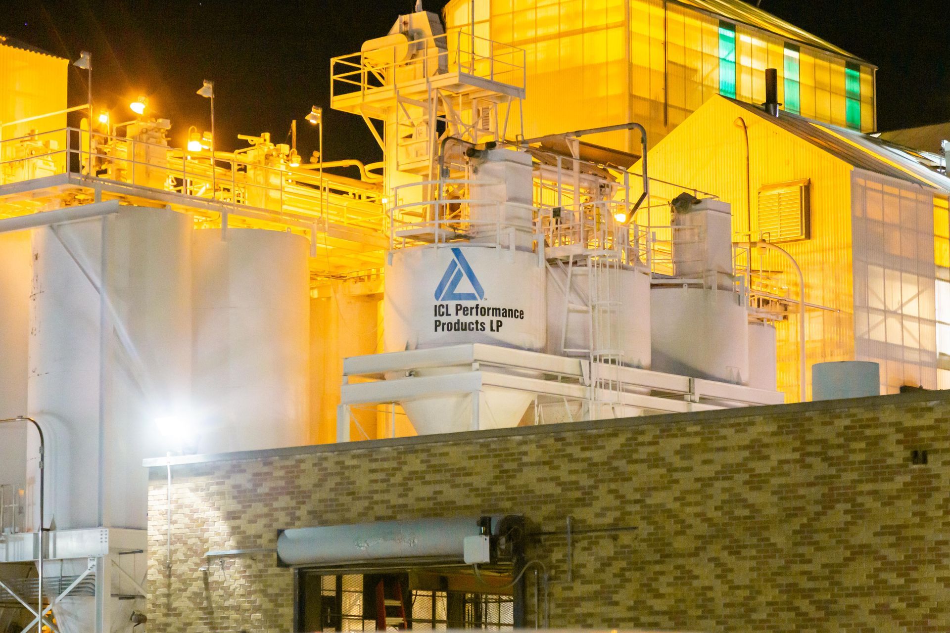 Professional photograph of the exterior of a factory at nighttime. 