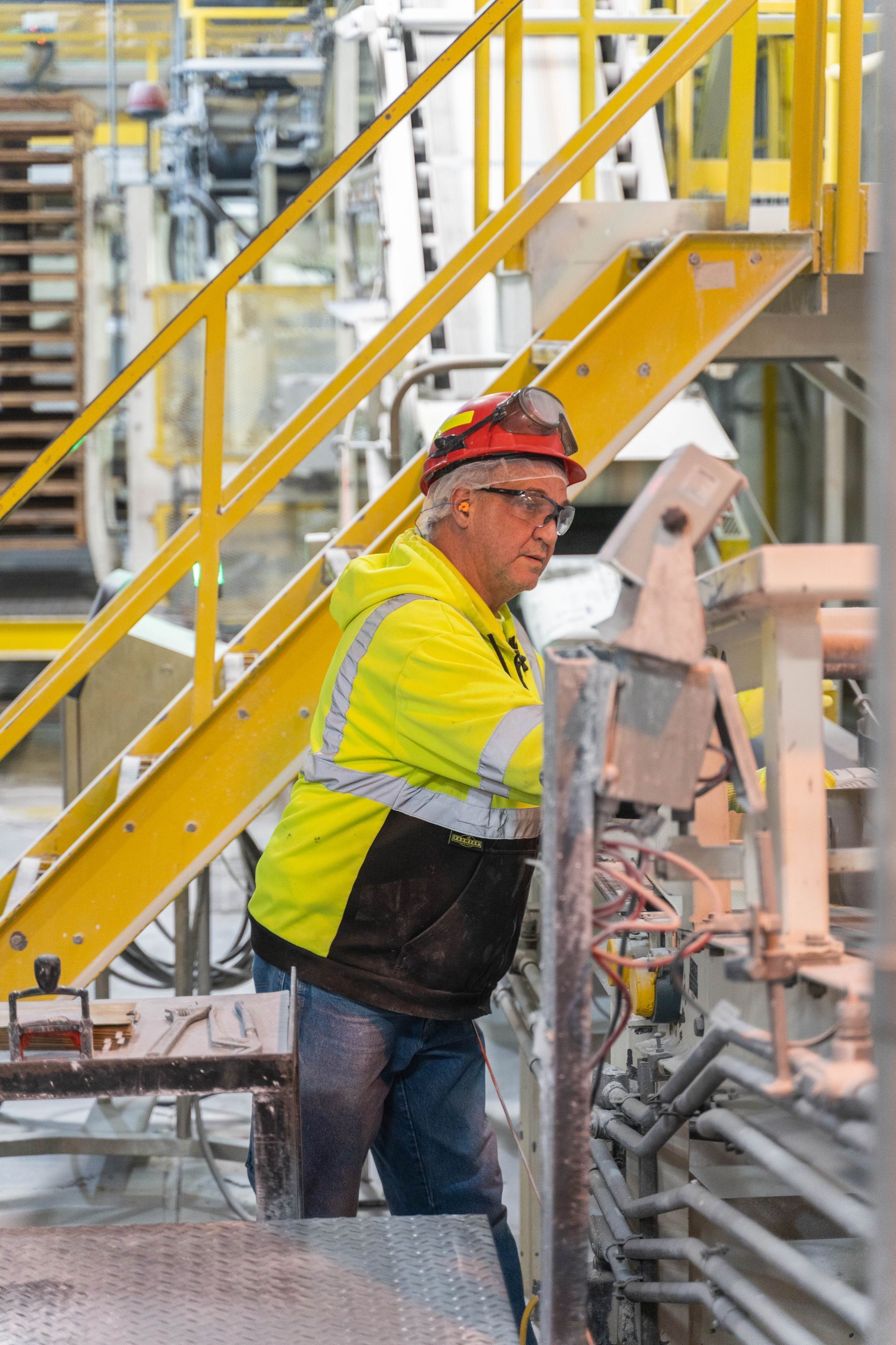 Professional photograph of a man in a hard hat working in a factory.