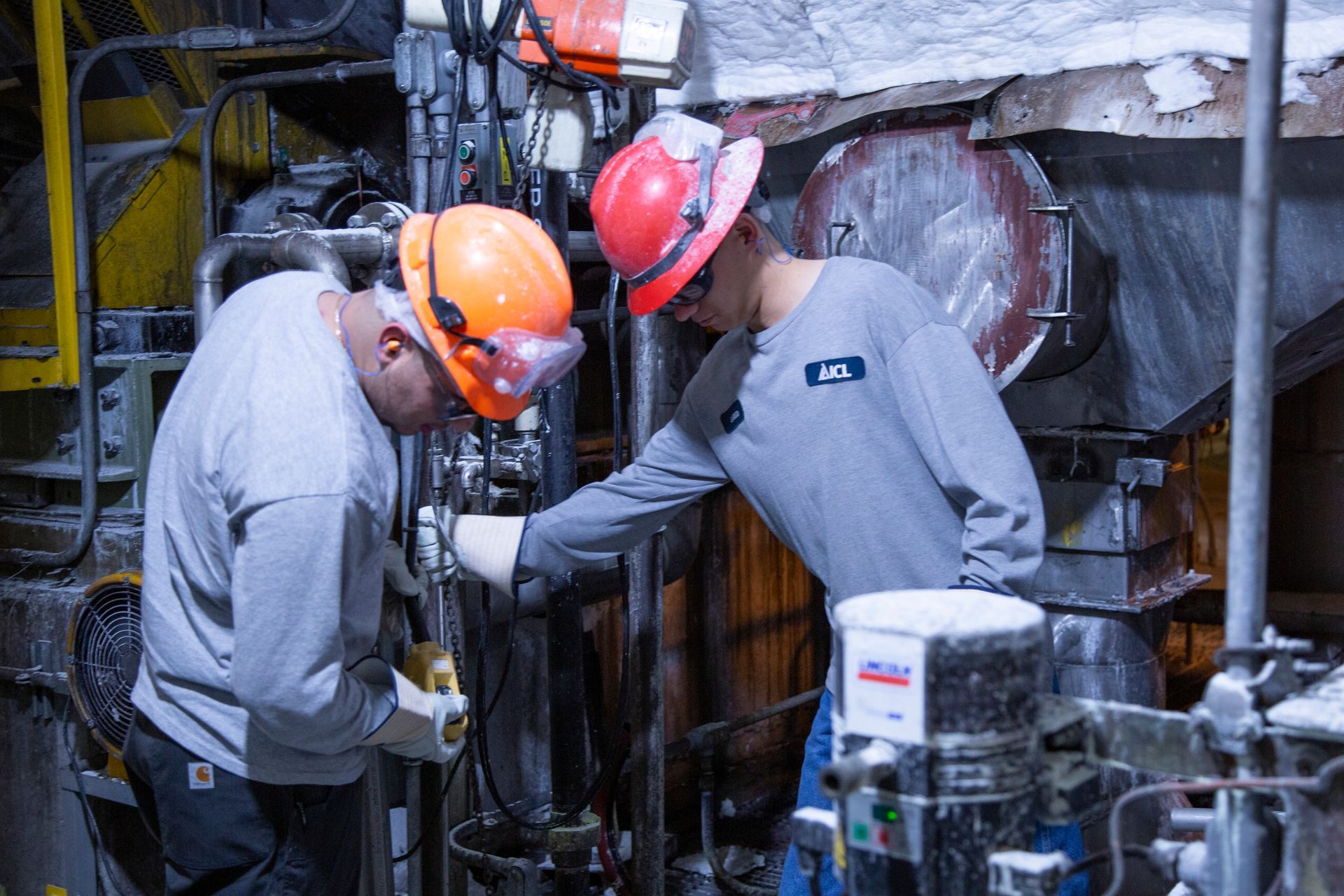 Professional photograph of two men working a large machine.