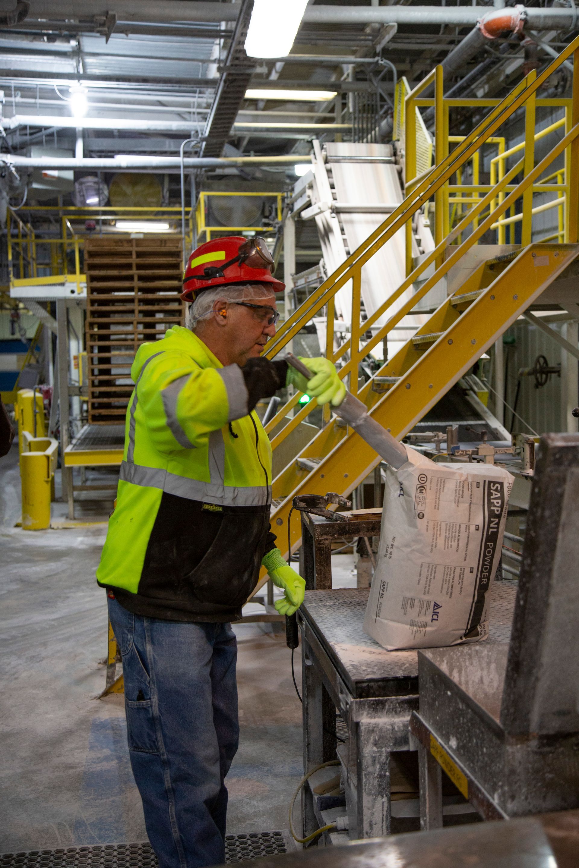 Professional photograph of a man in a hard hat opening a bag of industrial chemical.