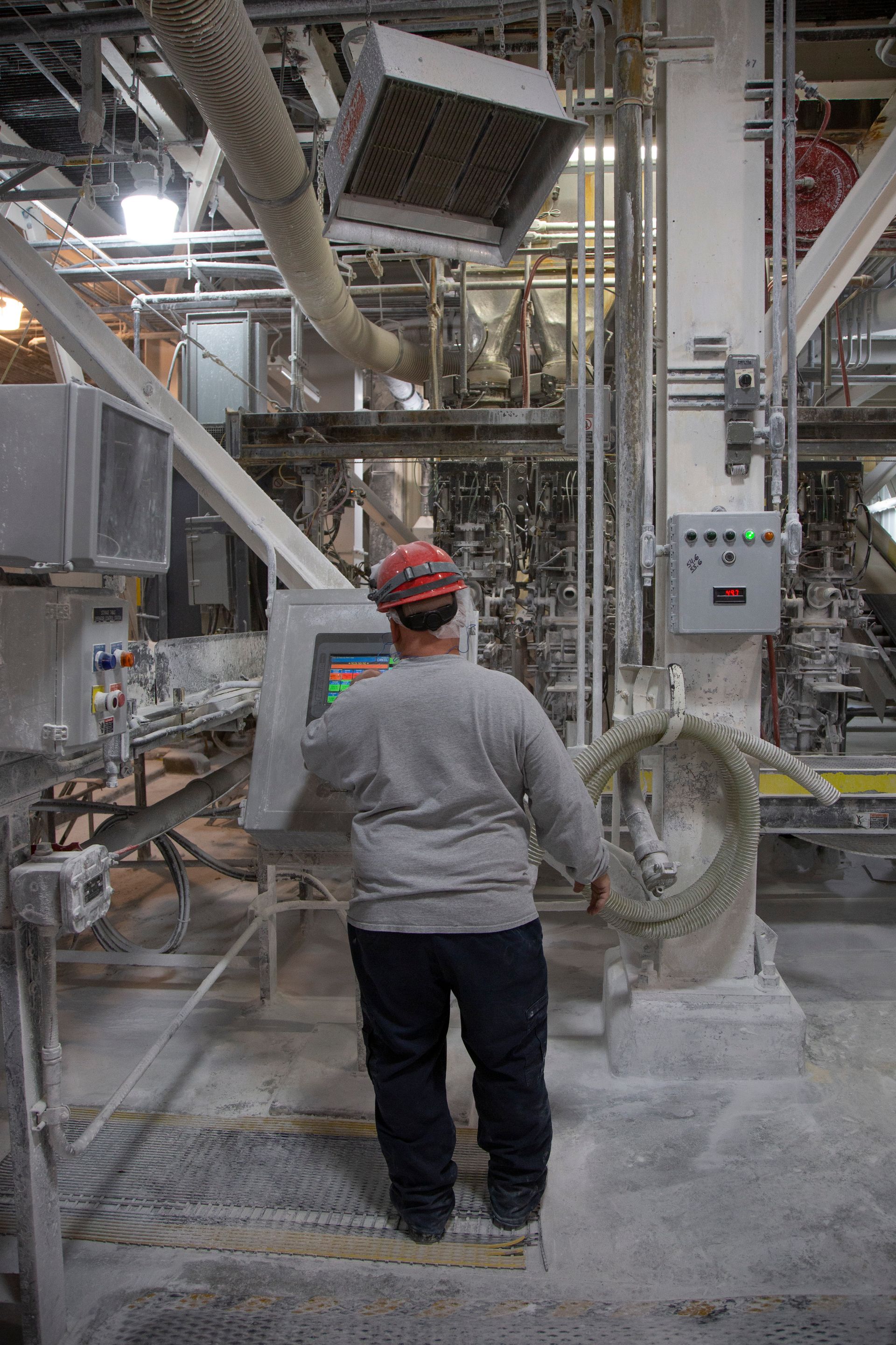 Professional photograph of a person in a hard hat working on a computer panel.