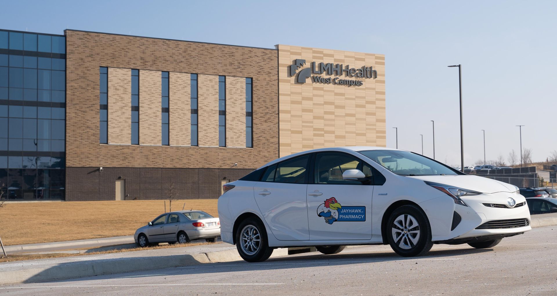 Professional photograph of a car with a logo sitting in front of a building.