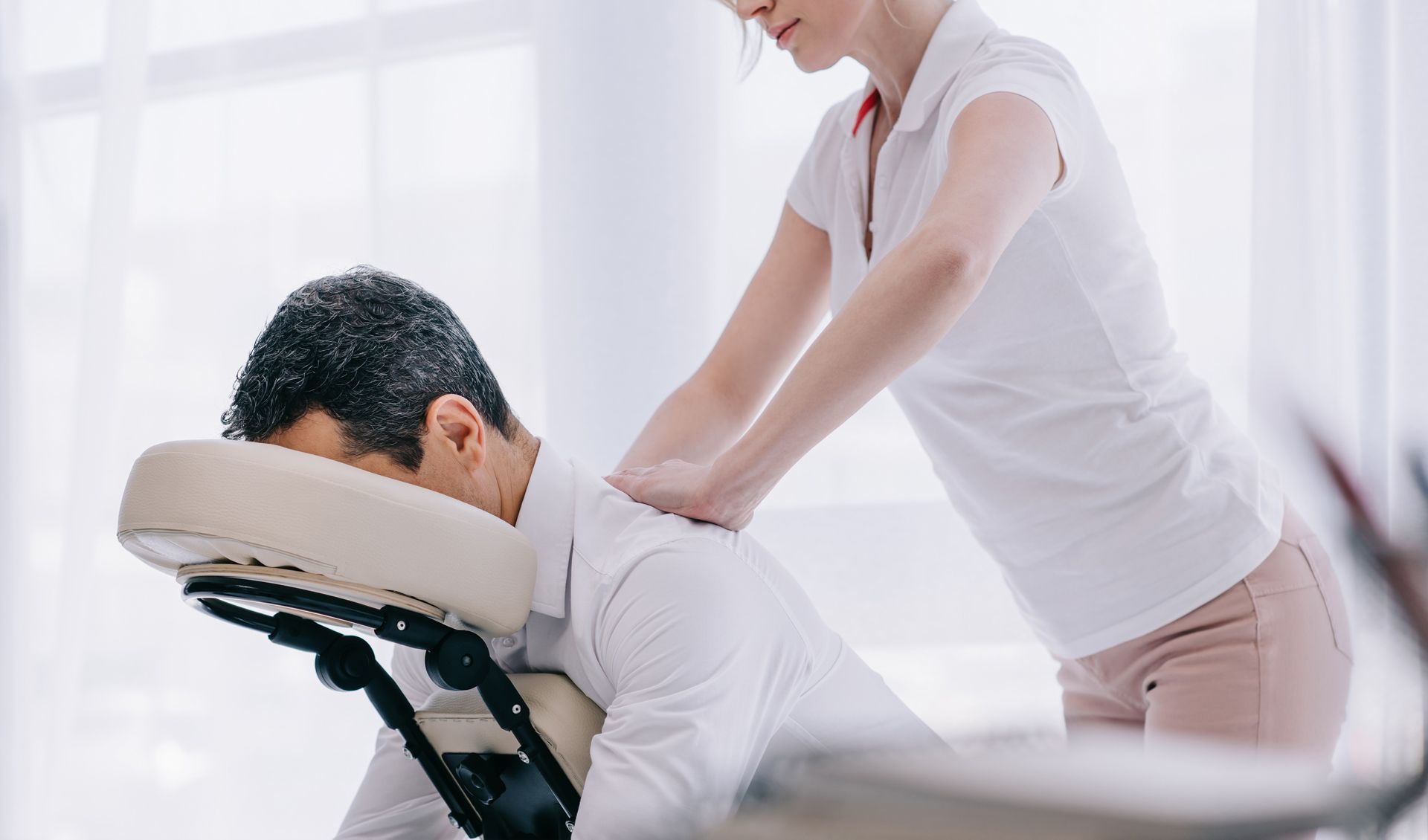 A woman is giving a man a massage in a chair.
