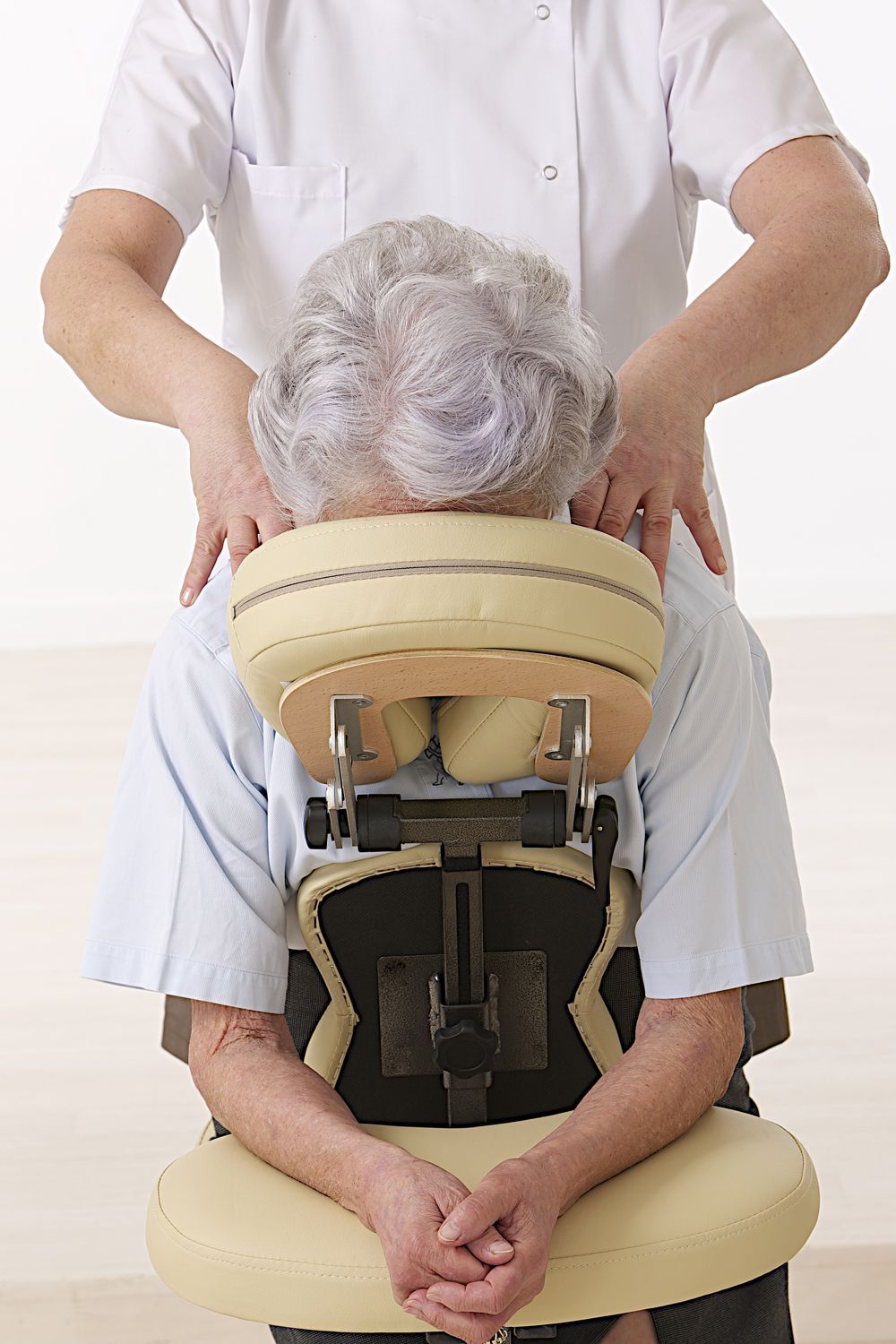 An older woman is sitting in a chair getting a massage.