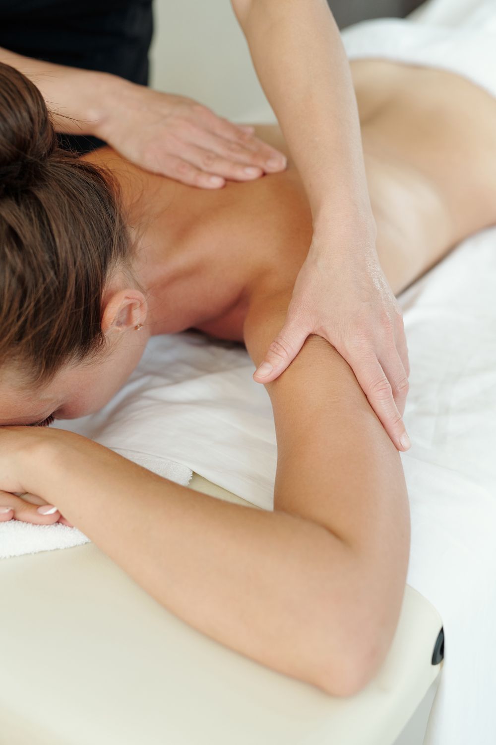 A woman is laying on a table getting a massage.