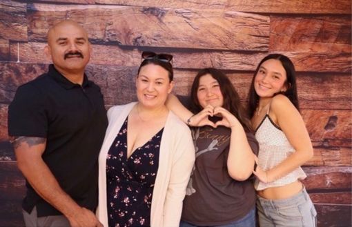 Family smiling and posing together in front of a wood-paneled wall