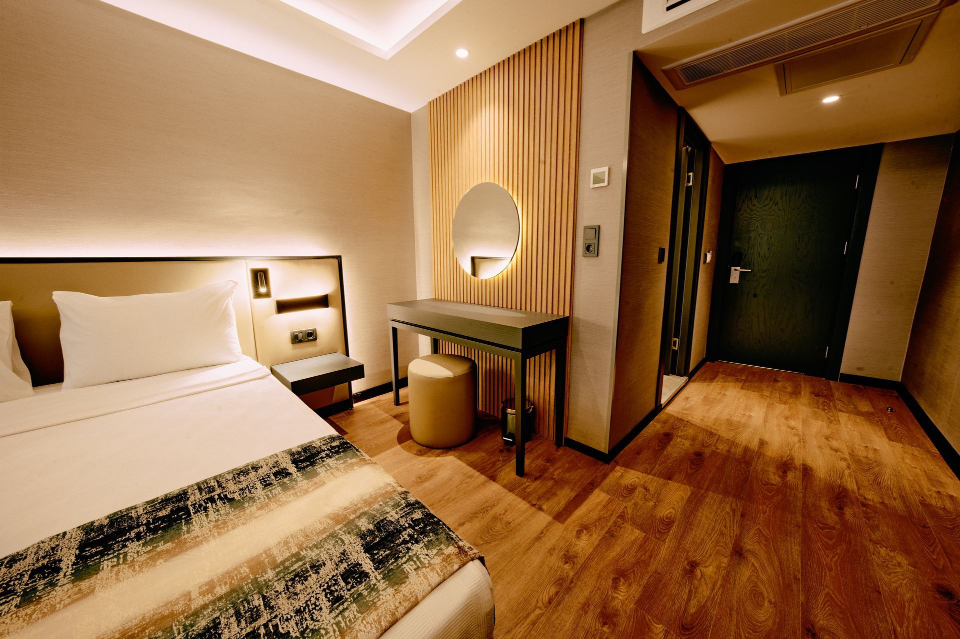A hotel room with a bed , dresser and mirror