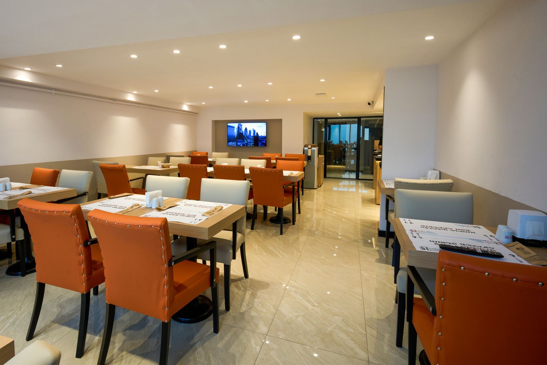 A restaurant with tables and chairs and a television on the wall.
