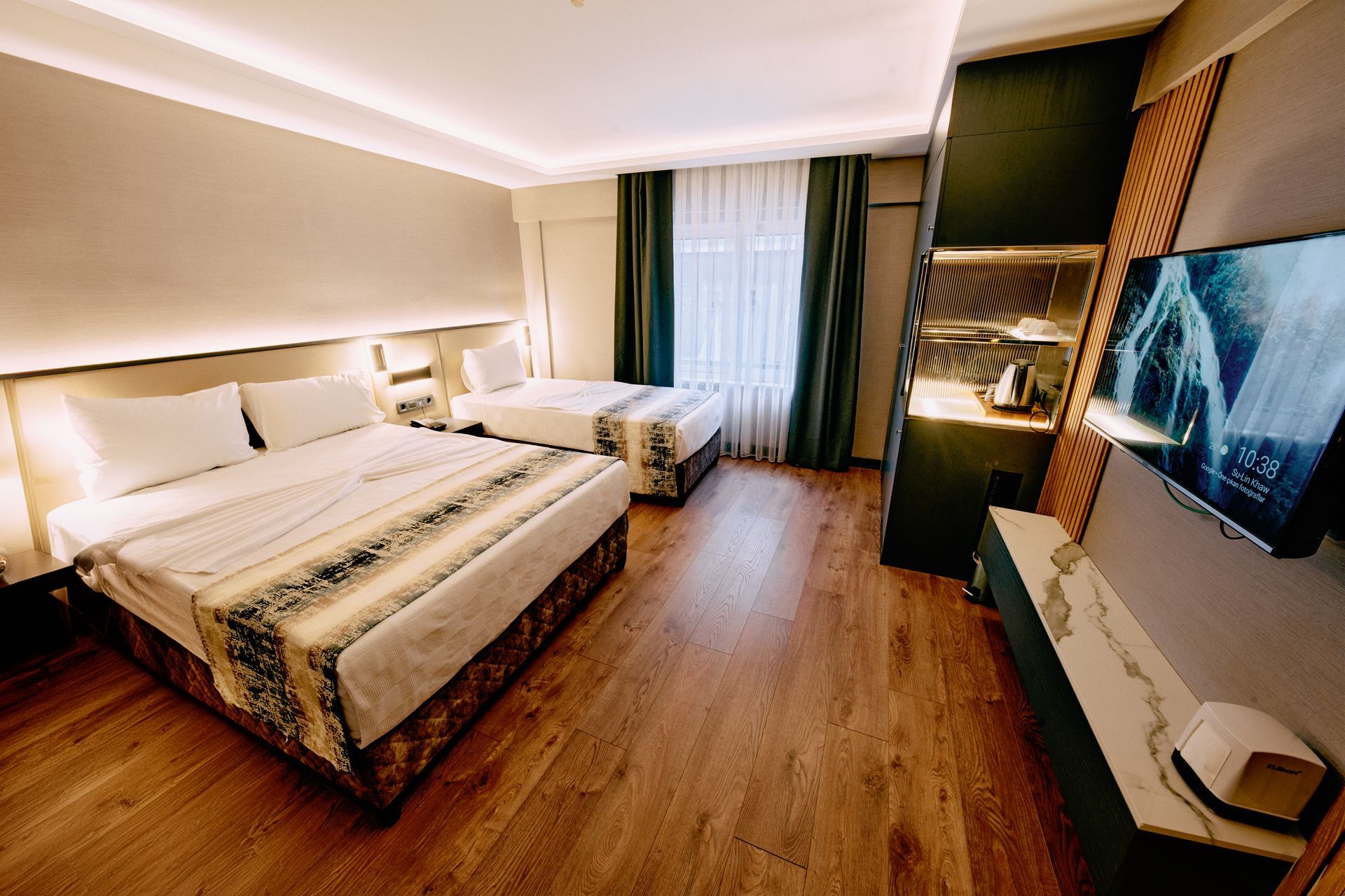 A hotel room with three beds and a flat screen tv.