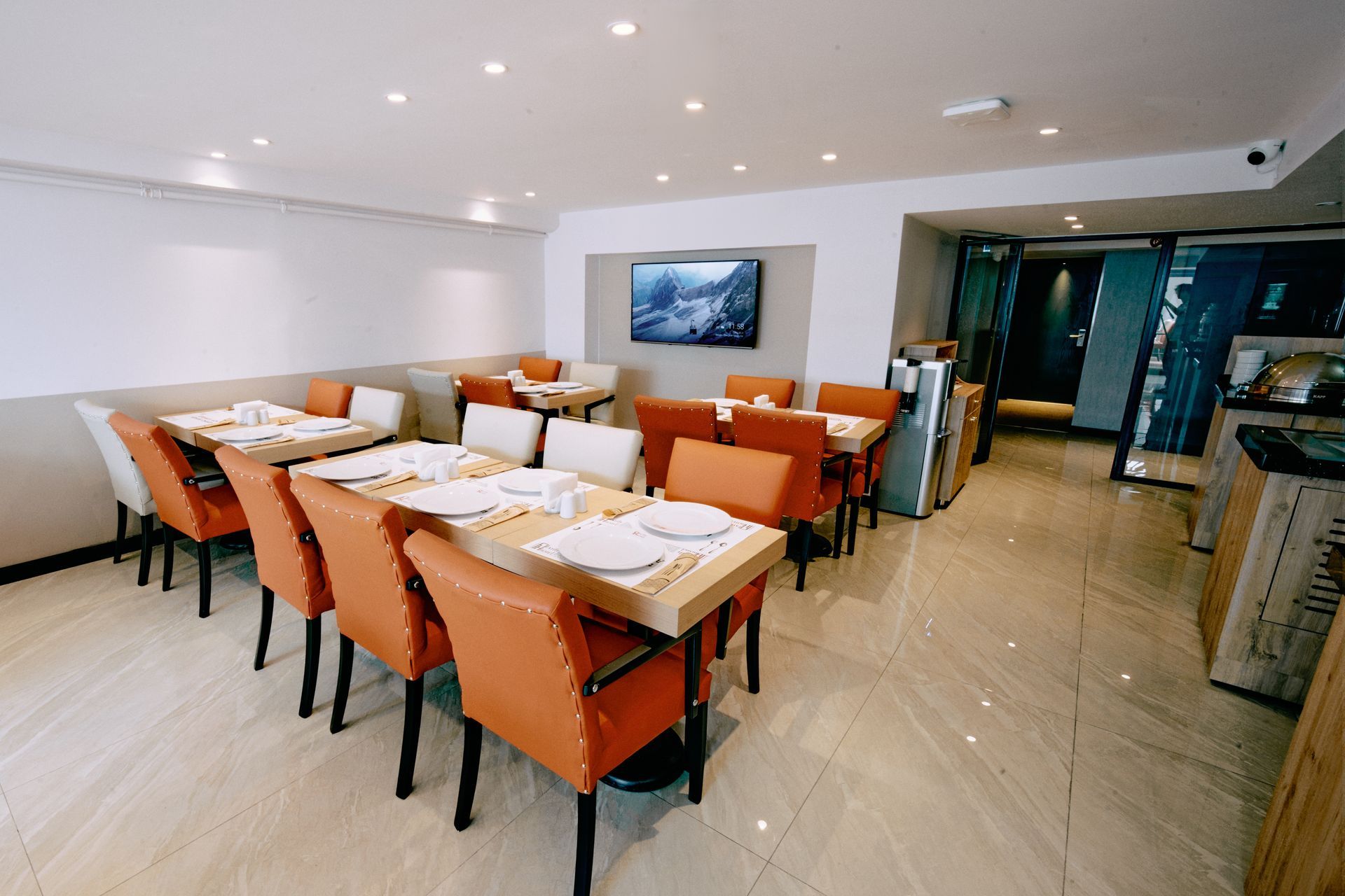 A restaurant with tables and chairs and a television on the wall.