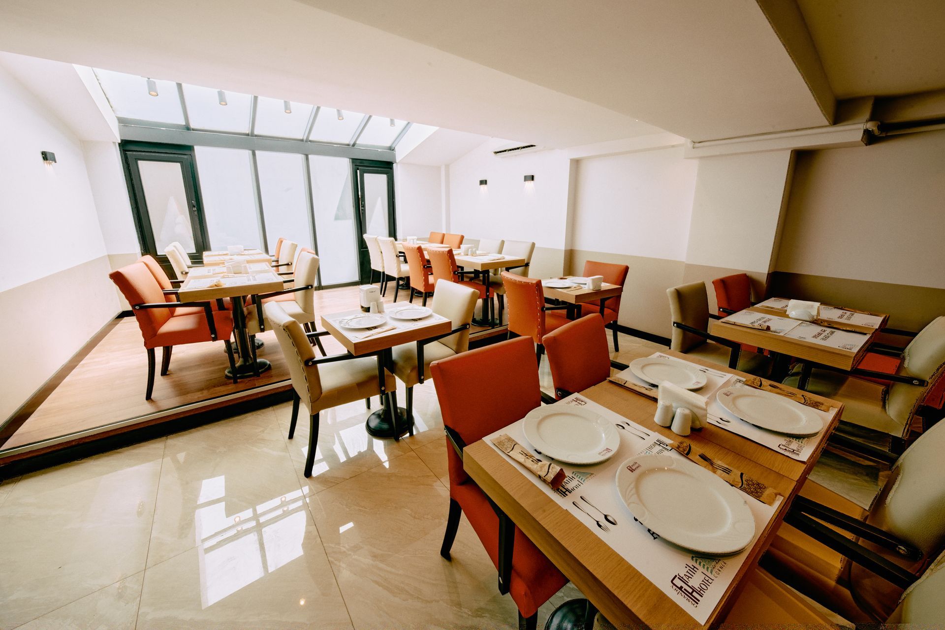A restaurant with tables and chairs and plates on them.