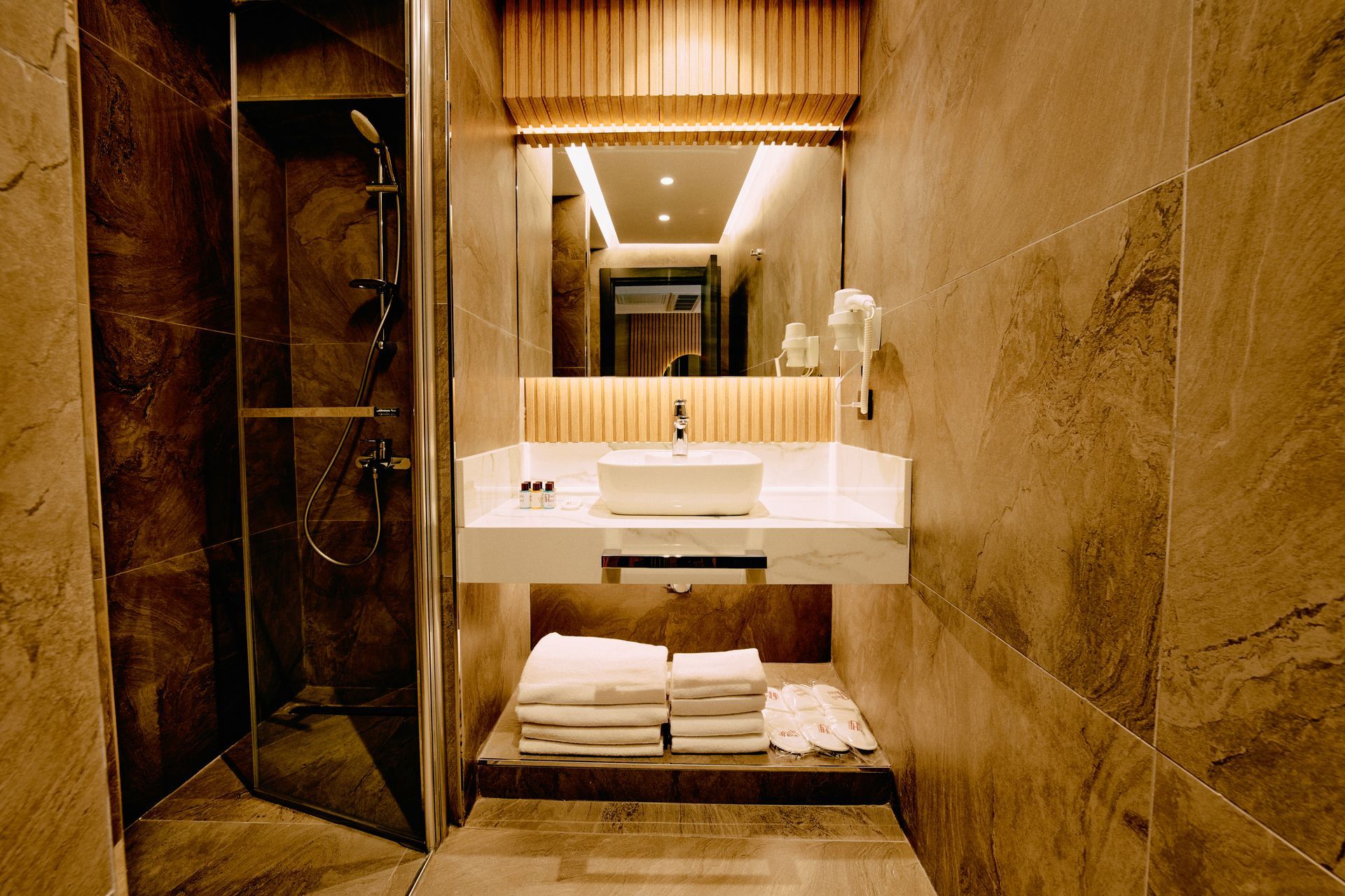 A bathroom with a sink , mirror and shower.