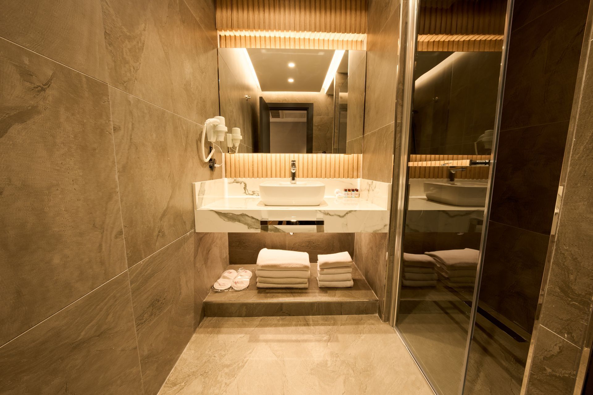 A bathroom with a sink , mirror and towels on the floor.