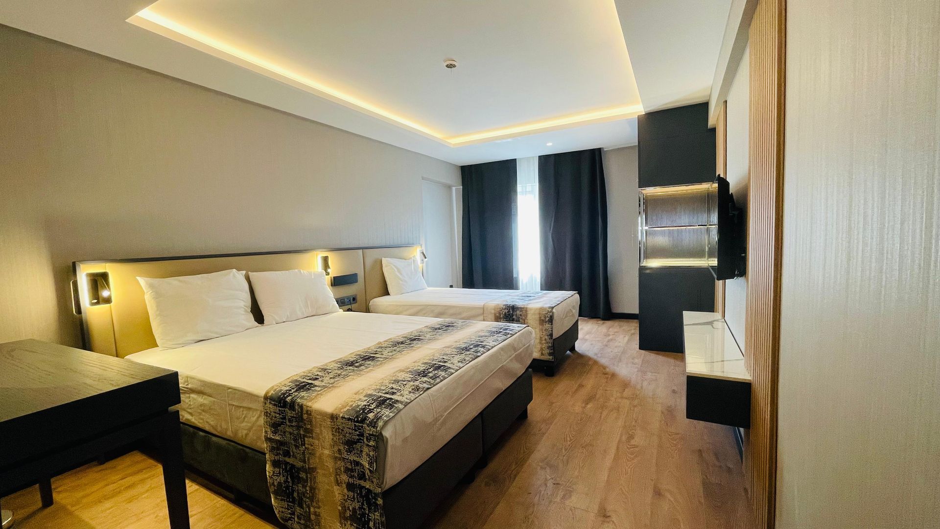 A hotel room with two beds , a desk and a television.