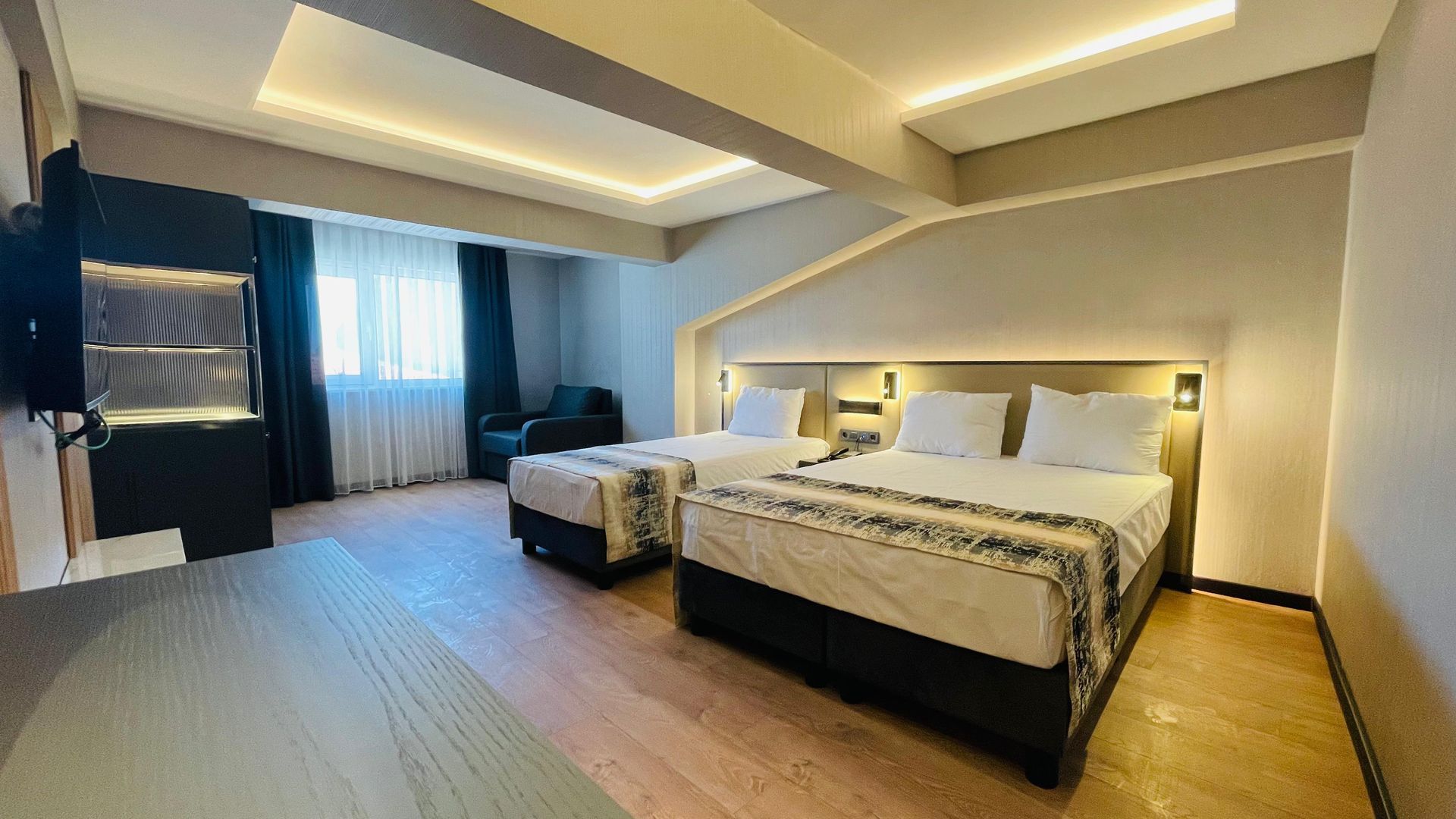 A hotel room with three beds and a television.