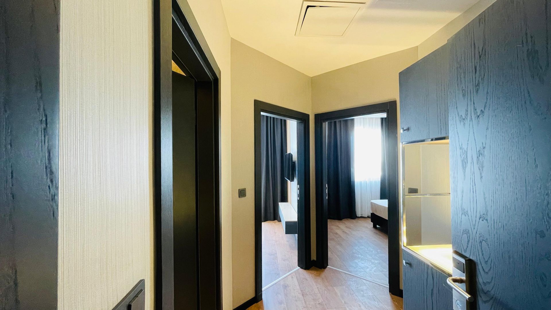 A hallway in a hotel room with a refrigerator and a fridge.