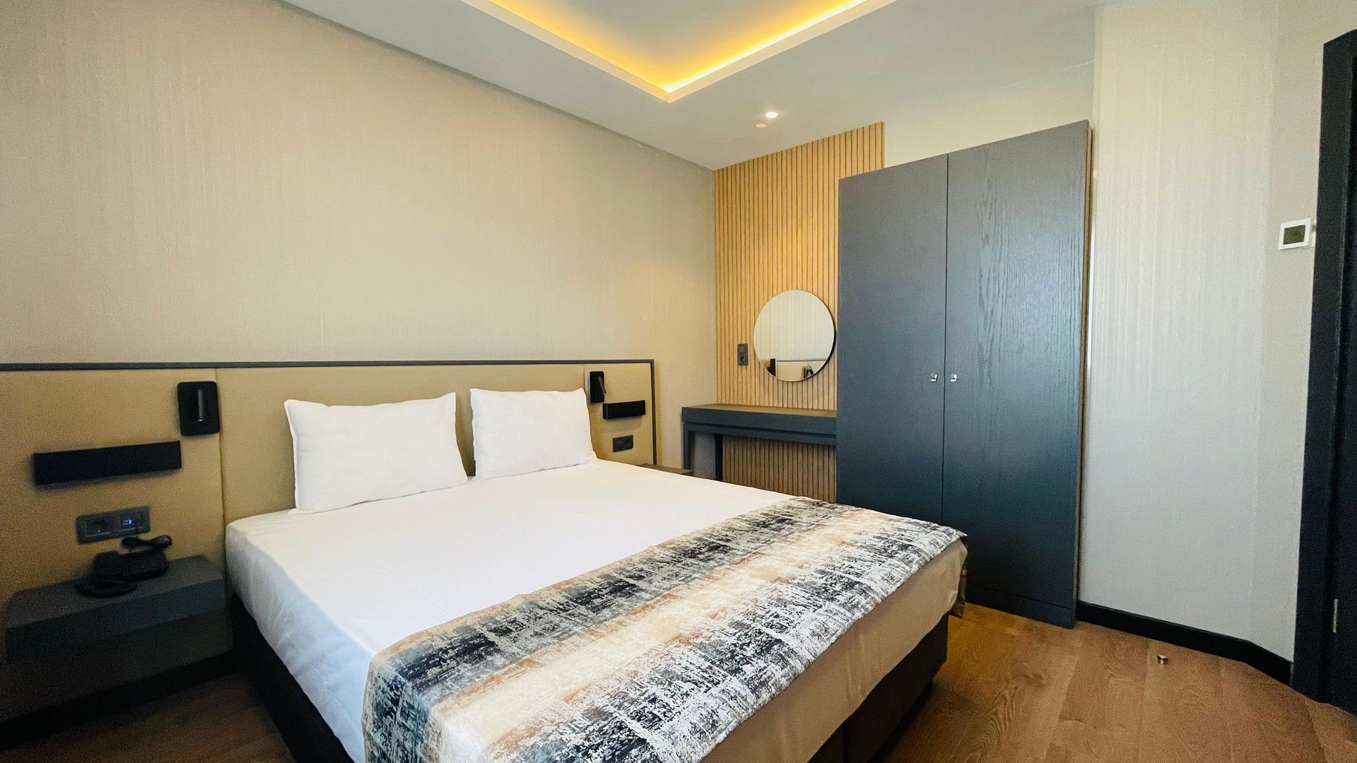 A hotel room with a king size bed and a wardrobe.