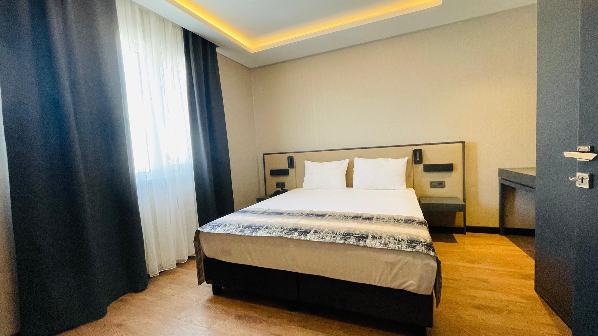 A hotel room with a large bed and a window.