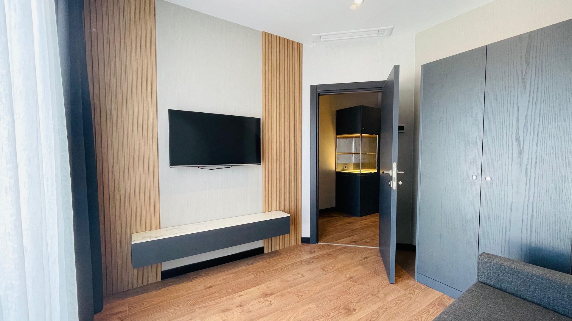 A living room with a flat screen tv on the wall and a couch.