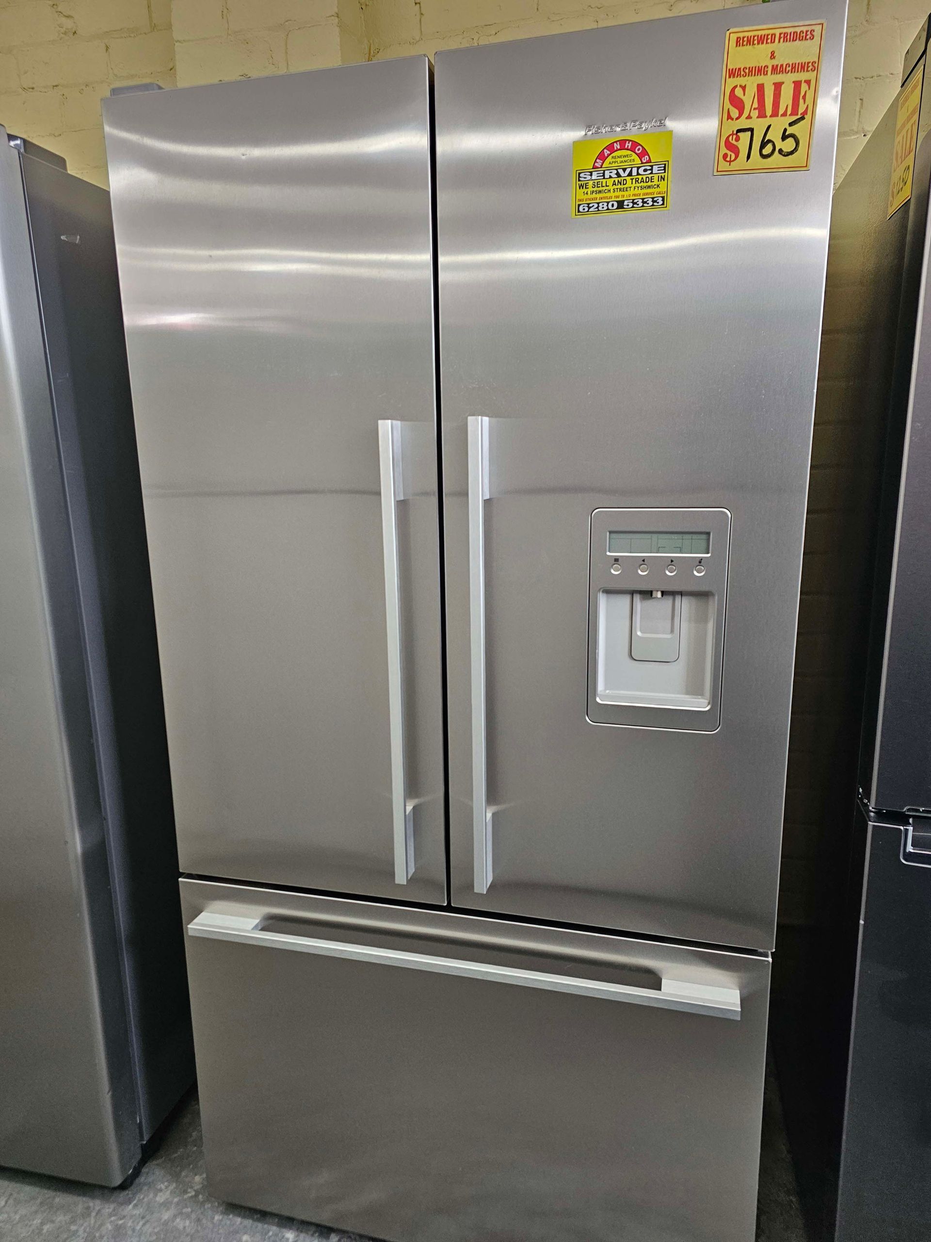 Stainless steel side-by-side refrigerator with water and ice dispenser, shown in a store display.