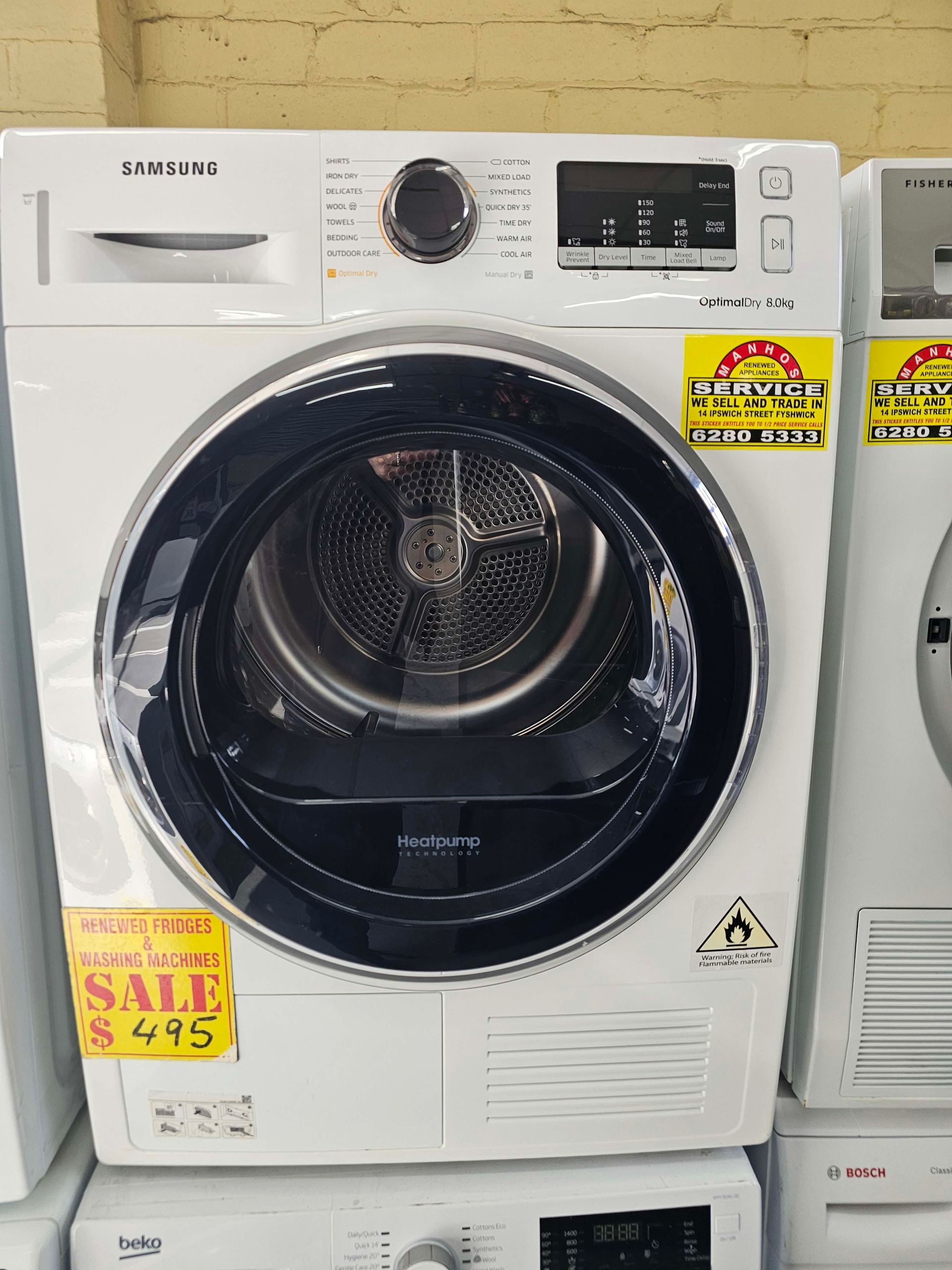 White Samsung front-load washer with black door and control dial on a showroom floor.