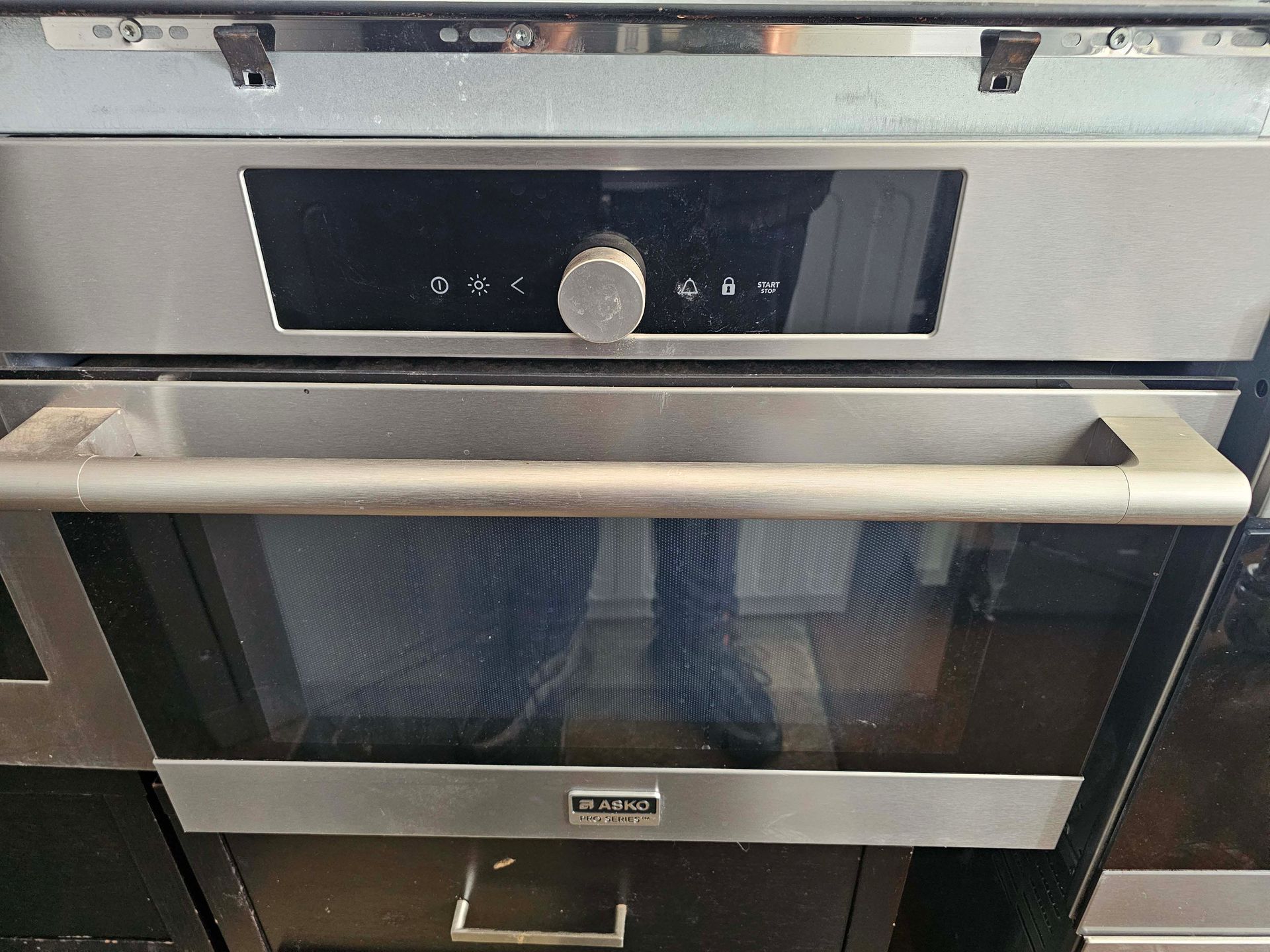 Built-in stainless steel oven with black glass door and control panel above handle