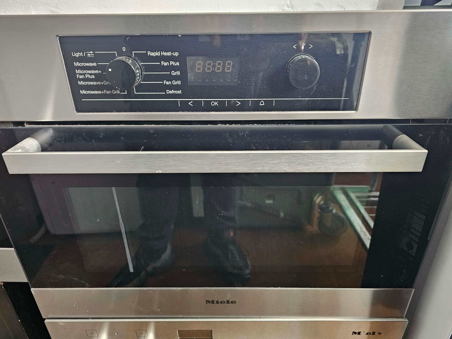 Built-in stainless steel oven with black glass door and control panel with knobs and digital display