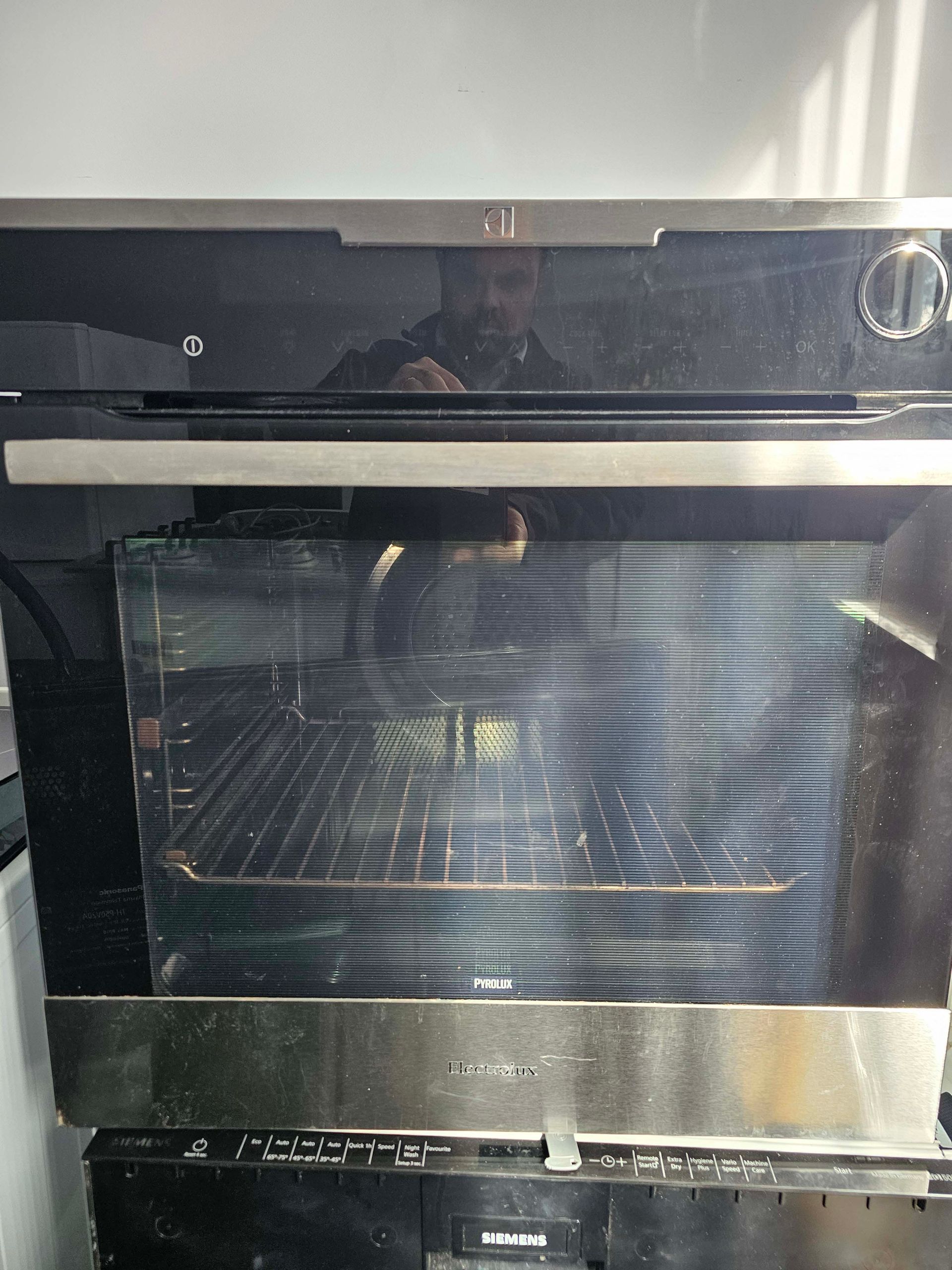 Stainless steel oven with glass door and control knobs in a kitchen.