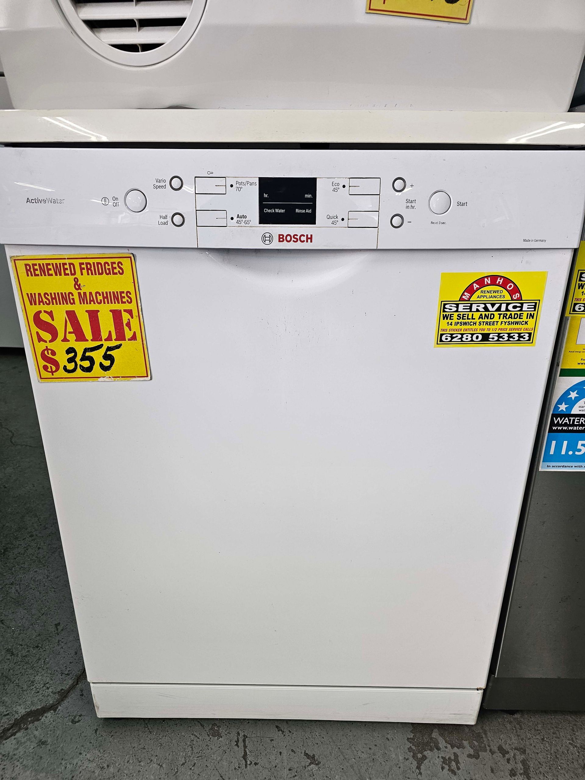 White front-load dishwasher with sale tags on display in an appliance store.