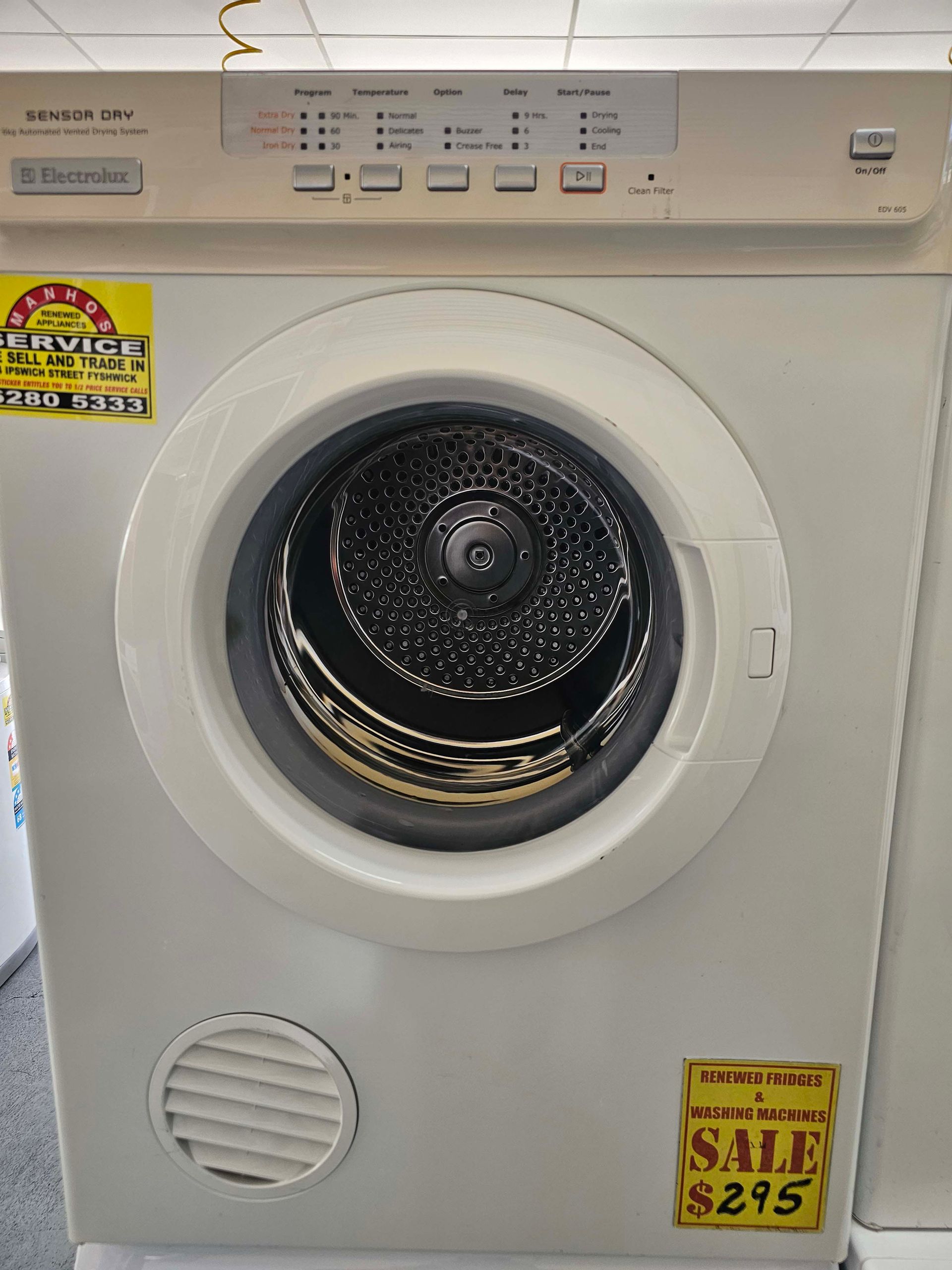 White front-loading dryer in a showroom with sale stickers on the front.